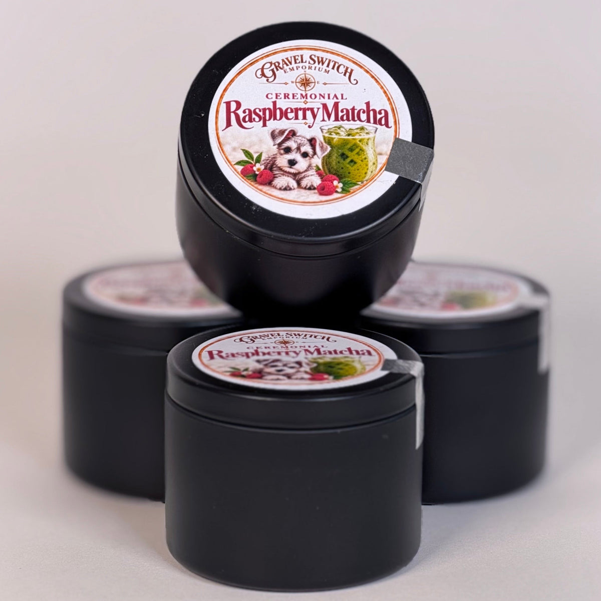 Three small round black jars of Basil Dental Original Raspberry Matcha toothpaste arranged on a light gray background, with one jar standing upright on top of the other two.