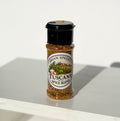 A clear plastic shaker bottle of Brian Speers Tuscany Spice Blend with a black lid, standing on a white surface against a white background.
