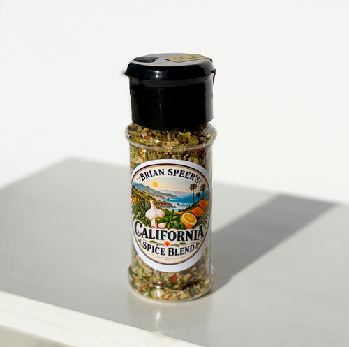A bottle of Brian Speers California Spice Blend seasoning with a black shaker cap and a colorful label, set on a white surface with a soft shadow.