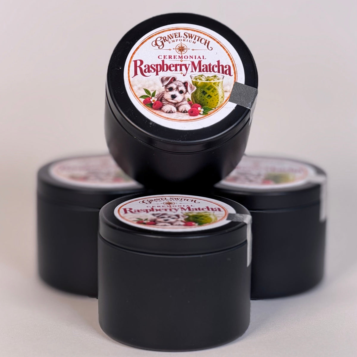 Three small round black jars of Basil Dental Original Raspberry Matcha toothpaste arranged on a light gray background, with one jar standing upright on top of the other two.